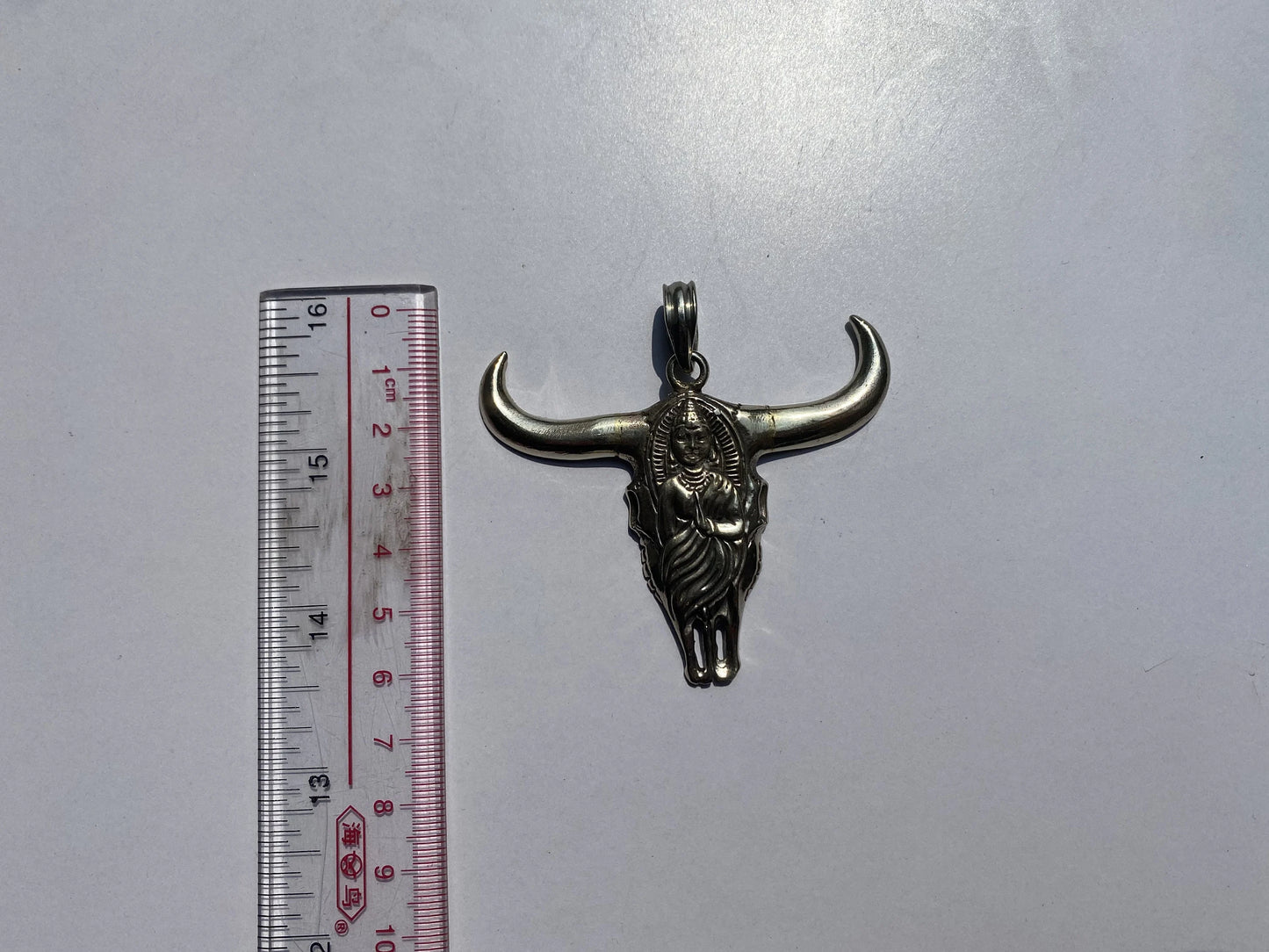 Large Horn Bull with buddha carved inside it symbolizing fertility of the earth and representing earthly passions, silver pendant.