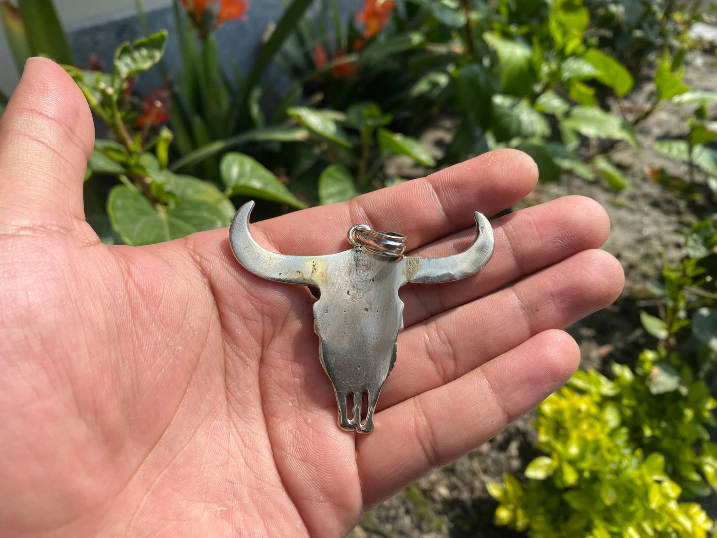 Large Horn Bull with buddha carved inside it symbolizing fertility of the earth and representing earthly passions, silver pendant.